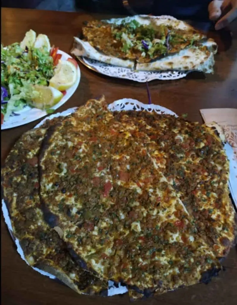 Crispy lahmacun stacked on a tray with a side salad and lemon at Çıtır in Beşiktaş
