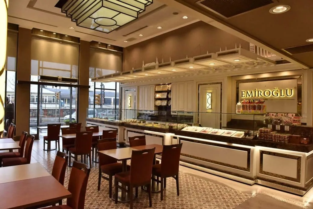 Dining tables and a long dessert counter inside an Emiroğlu Baklava branch