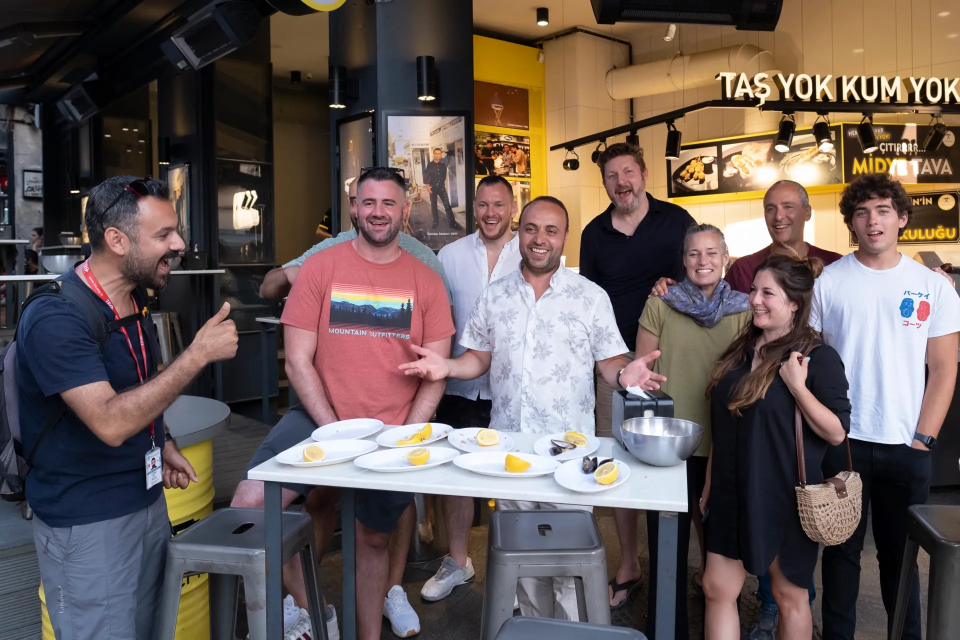 A happy tour group gathered around a table of stuffed mussels at an Istanbul restaurant