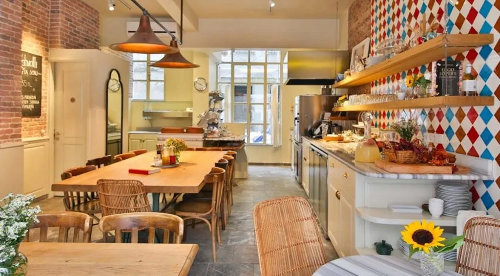 Forno Balat's bright interior with a long communal wooden table, an open kitchen, and a red and blue harlequin-tiled wall