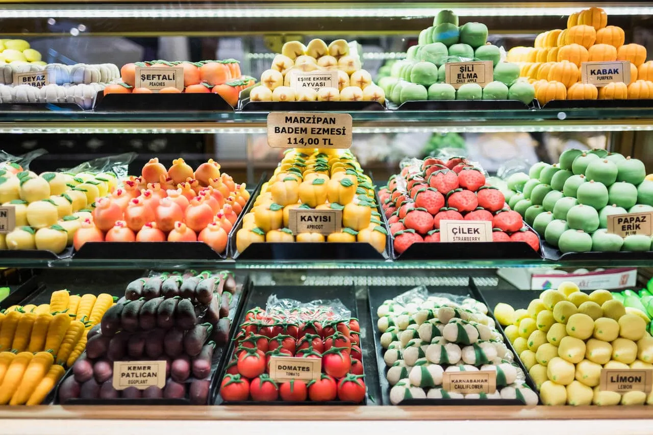 Variety of small brightly colored marzipan fruit sculptures on display in cabinet during Istanbul culinary tour