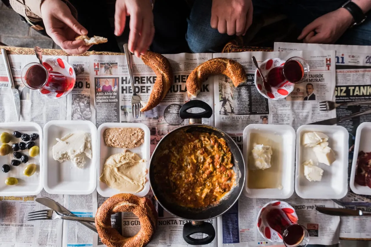 Taste of Two Continents food tour market breakfast of olives cheese eggs cream honey simit Turkish tea laid on newspaper