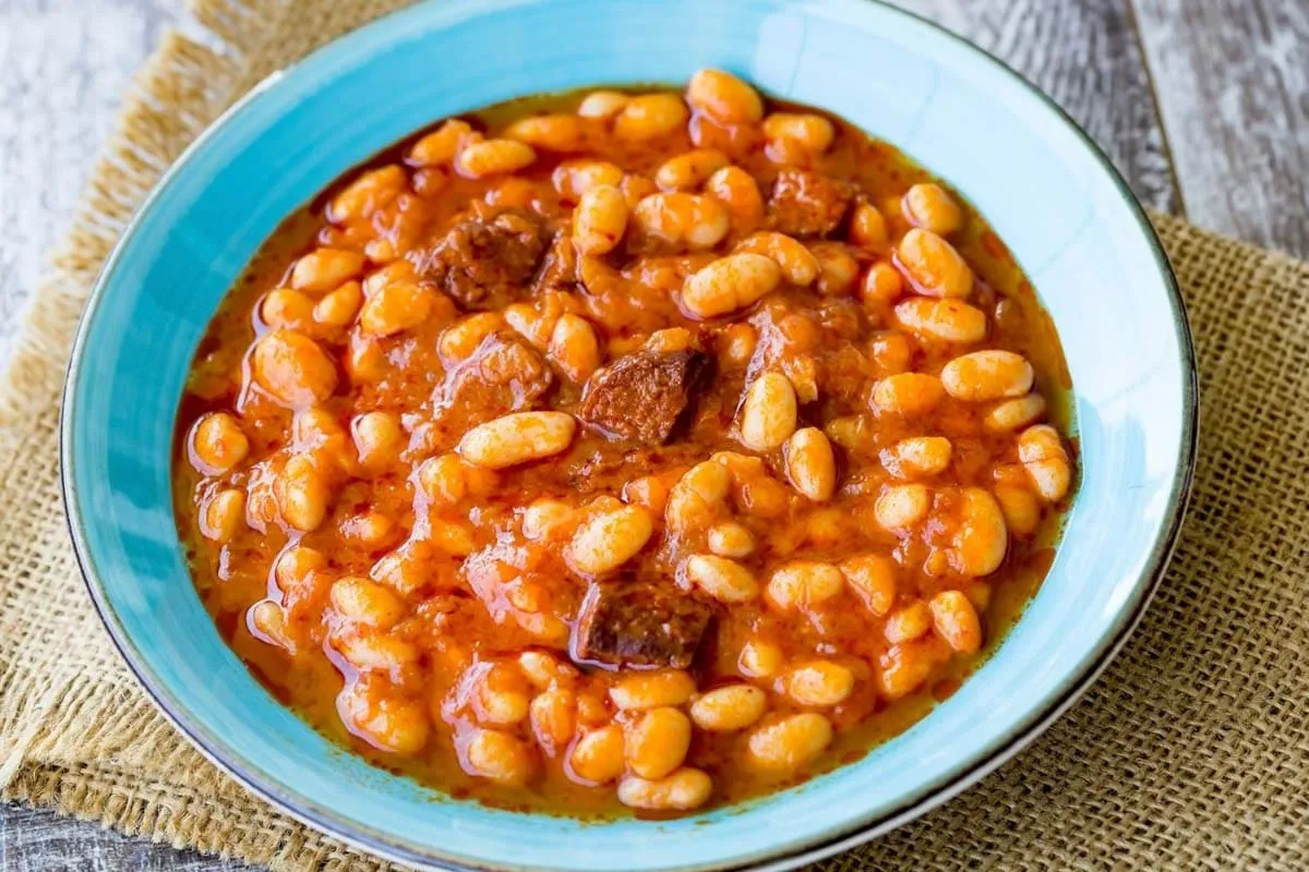 Turkish kuru fasulye white bean stew with meat chunks in tomato sauce, in a turquoise bowl