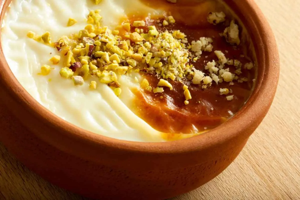 Baked sütlaç rice pudding in a clay bowl topped with crushed pistachios and a caramelized brown top