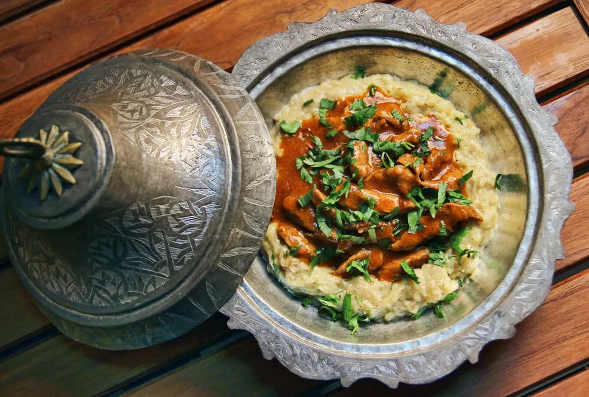Hunkar begendi with stewed meat over creamy eggplant in an engraved copper dish on wood