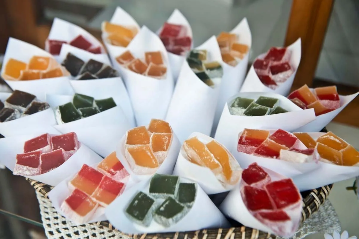 Colorful cubes of Turkish delight in white paper cones arranged in a woven basket