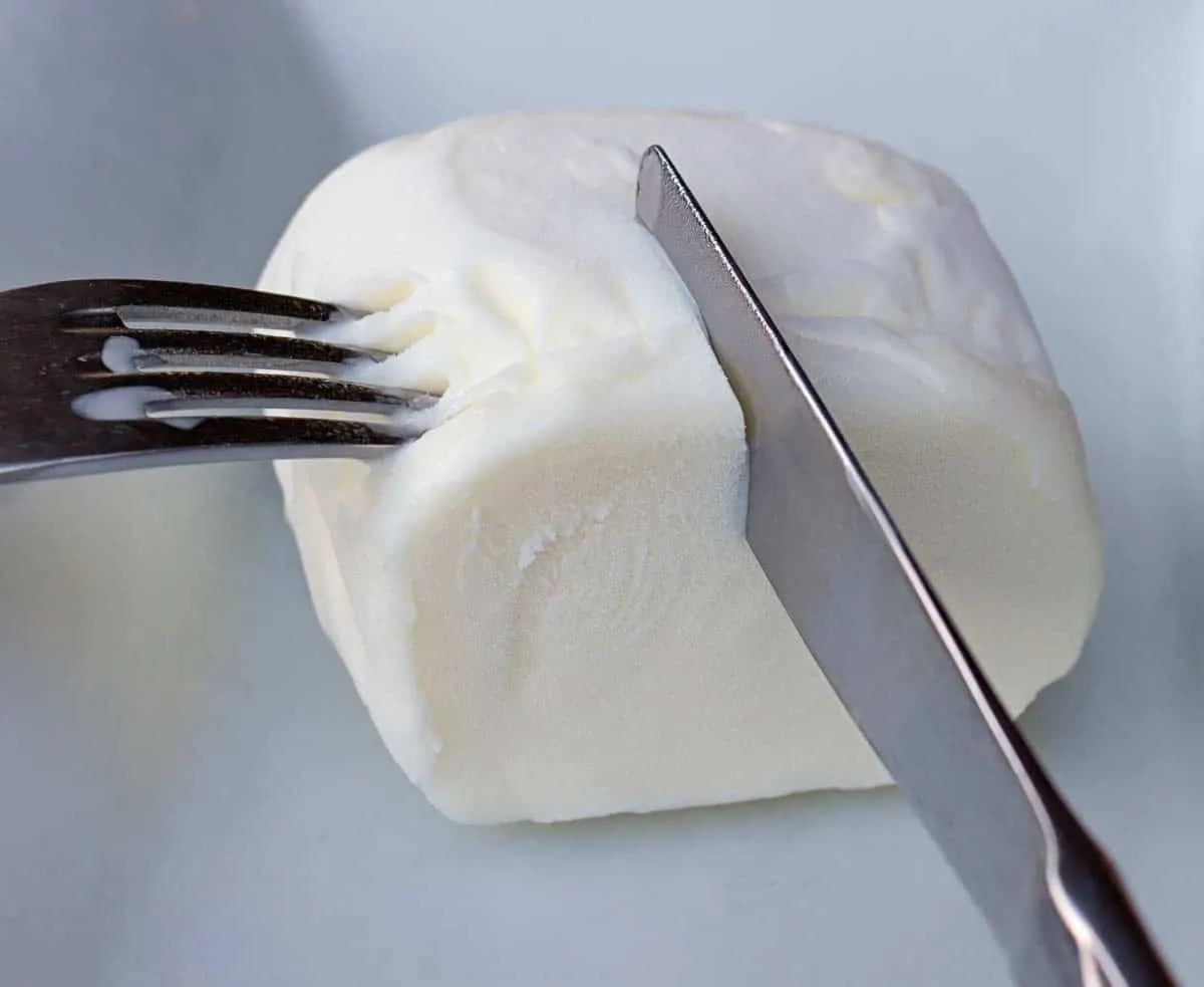 Knife and fork cutting into a dense white block of stretchy Turkish ice cream