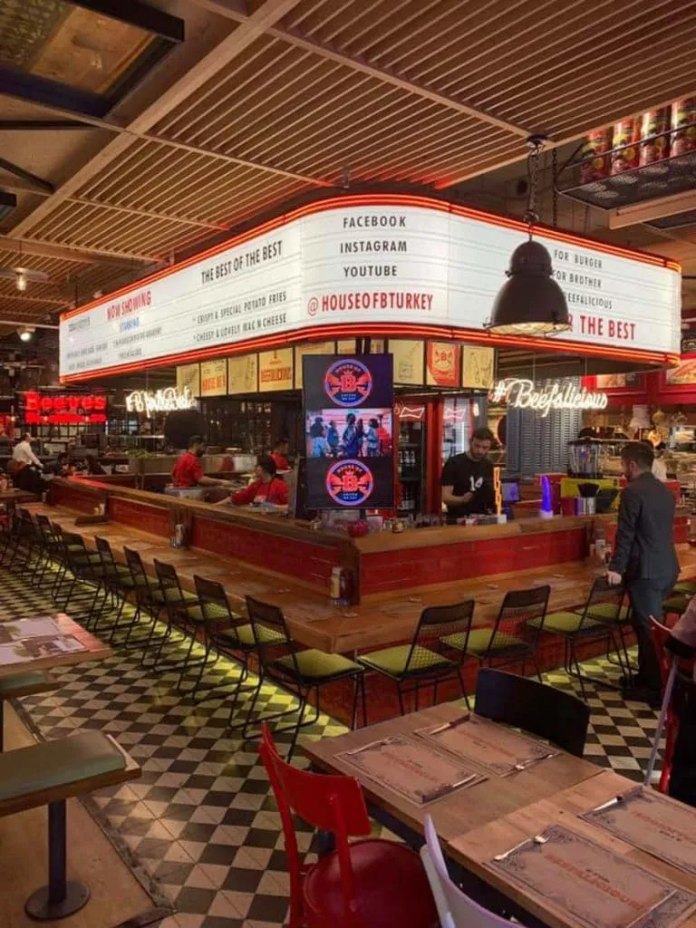 Retro diner room at House of B with a cinema-style marquee sign, red counter seating, and checkerboard floor
