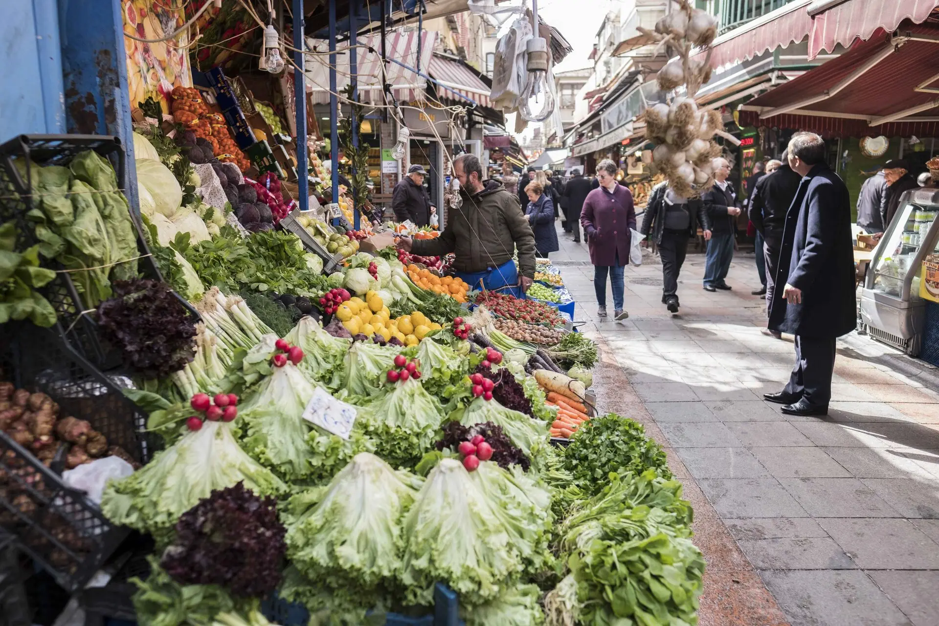 Fresh produce stalls along a busy Kadıköy market street in Istanbul, with shoppers passing by
