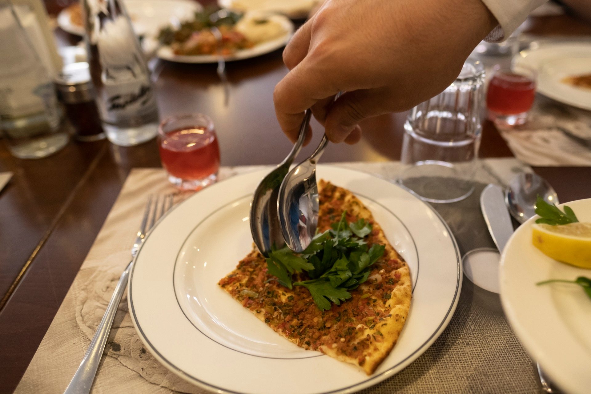 Lahmacun on a plate with a fresh parsley sprig at a set table in Istanbul