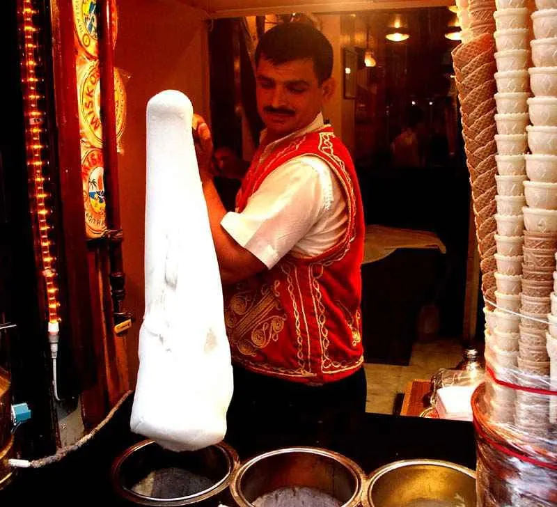 Dondurma master is stretching Turkish ice-cream with large paddle