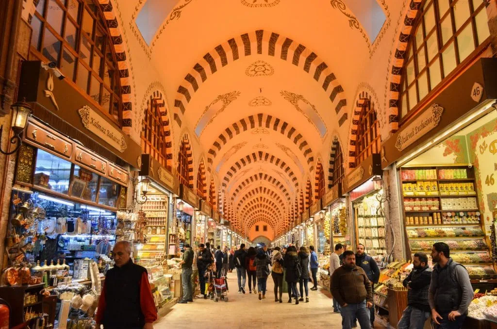 Lane inside istanbul spice bazaar, people walking past shops lining either side and traditional arched ceiling