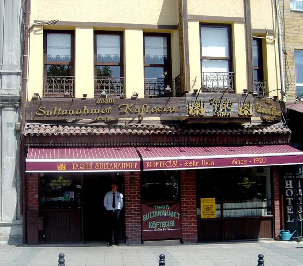 Storefront of Tarihi Sultanahmet Köftecisi Selim Usta with its dark red Since 1920 awning and carved wooden sign