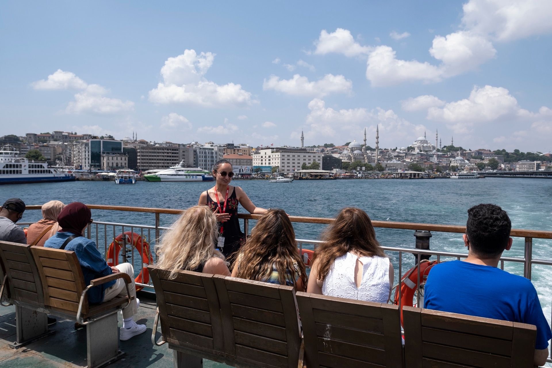 Tour group seated on a ferry deck with the Istanbul skyline behind